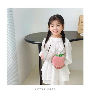 Close-up of pink peach-shaped crossbody bag with pearl chain strap for girls