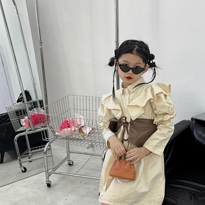 Girl's beige frill sleeve dress with brown leather corset belt and mini orange handbag
