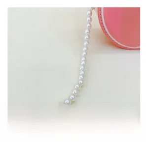 Detail of pink round purse showing white artificial pearl strap and fine stitching
