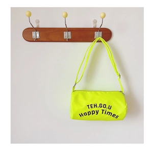 Détail du sac cylindrique vert fluo en toile avec lettrage noir et sangle réglable