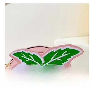 Close-up of fine stitching on a pink peach-shaped handbag with a gold metal chain buckle