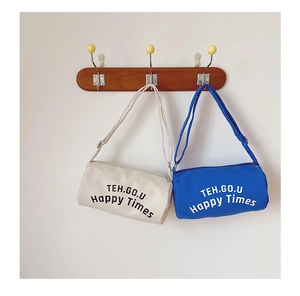 Vue détaillée des sacs bandoulière cylindriques en toile blanc cassé et bleu roi