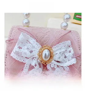 Gros plan du sac à main en dentelle rose avec poignée en perles et nœud décoratif blanc