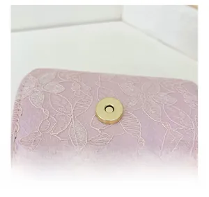 Détail de broderie en dentelle rose avec paillettes et fermoir magnétique doré