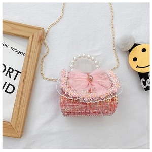 Detail of pink tweed girl's bag with pearl handle, lace bow and heart gemstone