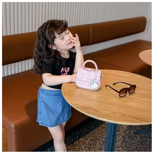 Detailaufnahme der rosa Mädchen-Handtasche mit 3D-Hasenprägung und süßem Kaninchenanhänger