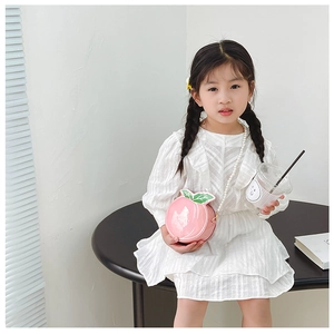 Detail of pink peach-shaped girls' bag with elegant white faux pearl chain strap