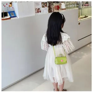 Girl wearing a bright neon green mini crossbody bag with a pink buckle over a white lace dress