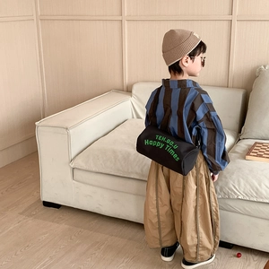 Sac cylindrique en toile noire pour enfants avec lettrage vert porté par un garçon