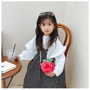 Detail of red apple shaped children bag with glossy finish and pearl chain strap
