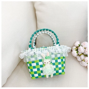 Détail d'un sac de plage tressé à damier vert avec un joli charm de lapin