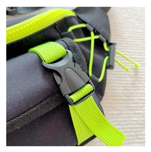Detail of black nylon chest bag with neon green zippers and plastic buckle closure