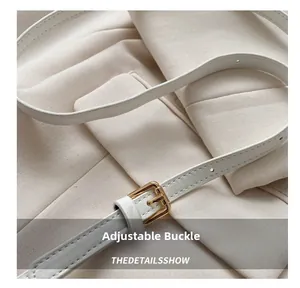Detail eines weißen Leder-Schultergurts mit goldener Schnalle und feinen Nähten