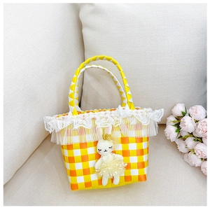 Détail du sac tressé à carreaux jaunes avec dentelle blanche et lapin en peluche