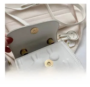 Detail der weißen Mini-Tasche mit goldenem Magnetverschluss und 3D-Hasenohr-Textur