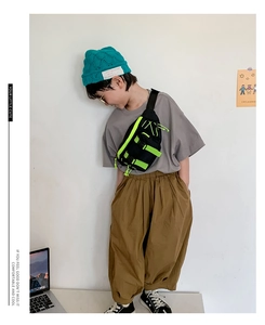 Kids tactical chest bag in black with neon green straps worn by child model