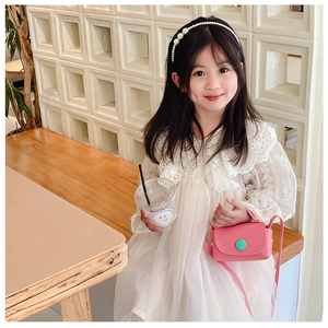 Pink mini crossbody bag for girls with a green buckle shown on a child model