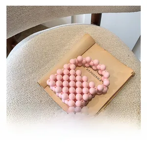 Close-up of pink beaded mini handbag for girls on vintage paper with soft lighting