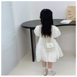 Vue détaillée du dos de la robe blanche à manches bouffantes avec sac à main perlé
