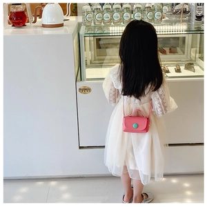 Back view of girl wearing a pink mini crossbody bag with a green contrast button detail