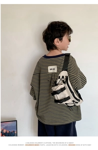 Detail of loose-fit green striped boy's t-shirt and off-white canvas crossbody chest bag