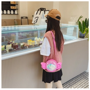 Detail of pink shell-shaped crossbody bag with pearl accents and decorative wings