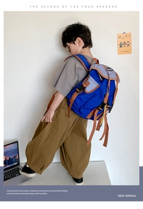 Detail view of a blue sporty kids backpack with contrast grey trim worn by a young boy