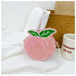 Detail of cute peach-shaped pink crossbody bag with green leaves and pearl chain strap