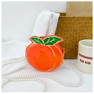 Detail of peach-shaped girls' crossbody bag with glossy patent leather and pearl chain