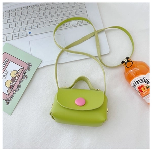 Close-up of avocado green mini leather bag with a large pink button in a clean setting