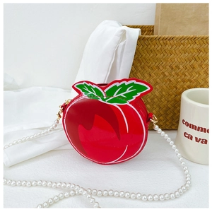 Detailed view of red peach crossbody bag with green leaf accent and pearl chain strap