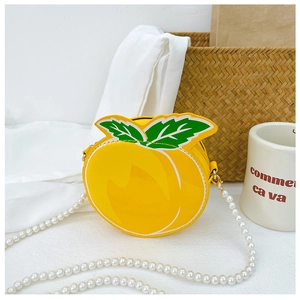 Close-up of a yellow peach-shaped crossbody bag with green leaves and pearl chain