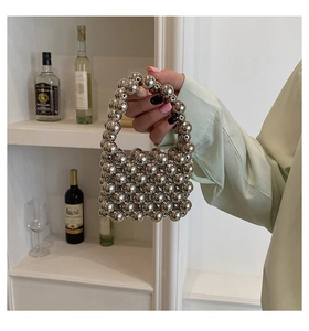 Detail of silver metallic beaded mini handbag with top handle held by a model
