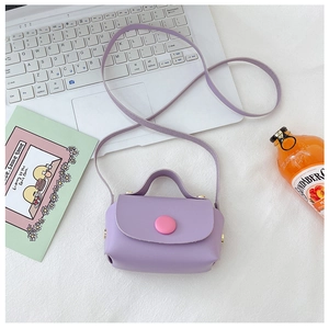 Detail of purple mini crossbody bag with pink buckle on white laptop lifestyle scene