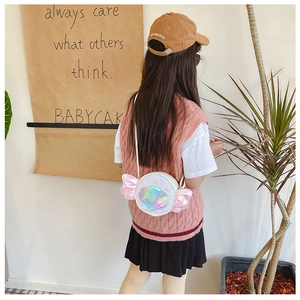 Detail of a girl wearing a white round crossbody bag with pink wings and shell accents