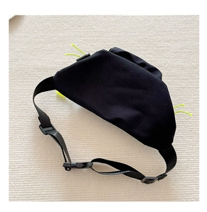 Detail of black nylon chest bag with fluorescent green zippers and adjustable buckle strap