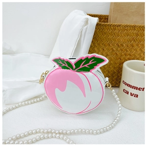 Close-up of peach-shaped girls crossbody bag with pearl chain and green leaf accents
