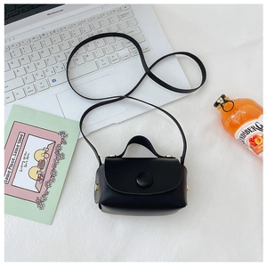Flat lay of a mini black PU leather crossbody bag with round buckle for girls