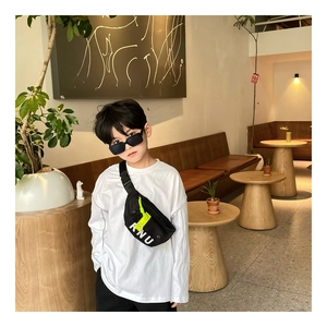 Enfant en t-shirt blanc et pantalon noir portant un sac bandoulière en toile avec KNU