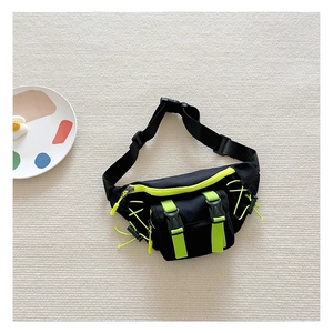 Overhead shot of a cool boy's canvas waist bag with neon green zippers on a textured rug