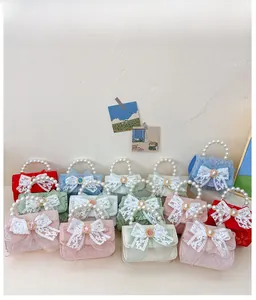 Détail de mini sacs en dentelle colorés avec grand nœud et poignées en perles nacrées