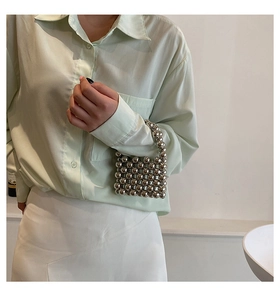 Close-up of a silver beaded mini handbag styled with a green shirt and white skirt