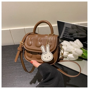 Detail der braunen Mini-Handtasche für Mädchen mit niedlichem Hasenrelief und Bogenanhänger