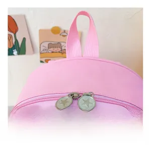 Détail de sac à dos rose en toile avec fermetures éclair étoile et poignée tissée