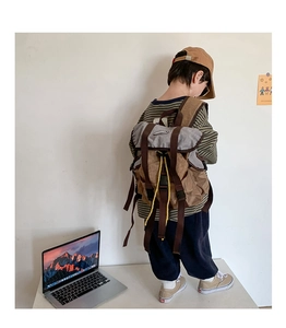 Rear view of child wearing a retro brown canvas backpack with yellow drawstring detail