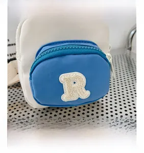 Détail d'un sac bandoulière enfant bicolore avec poche bleue et lettre R en bouclette