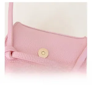 Dettaglio della pelle rosa martellata e della chiusura magnetica dorata di una mini borsa
