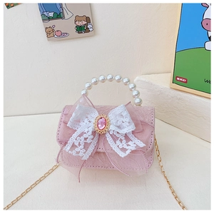Détail d'un sac à main rose pour enfant avec poignée en perles et nœud blanc à gemme