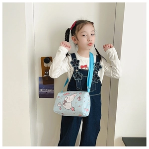Detail view of a cute cartoon bunny canvas bag worn by a young girl in a bright setting