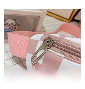 Détail de la fermeture éclair en métal et de la sangle rose sur le sac à damier rose